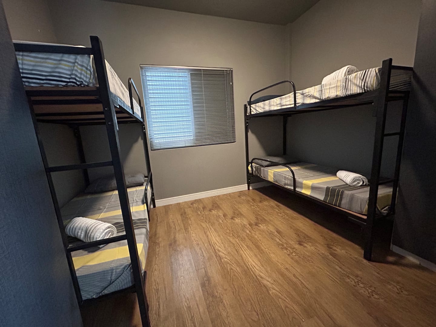 Quarto com beliches de metal e piso de madeira