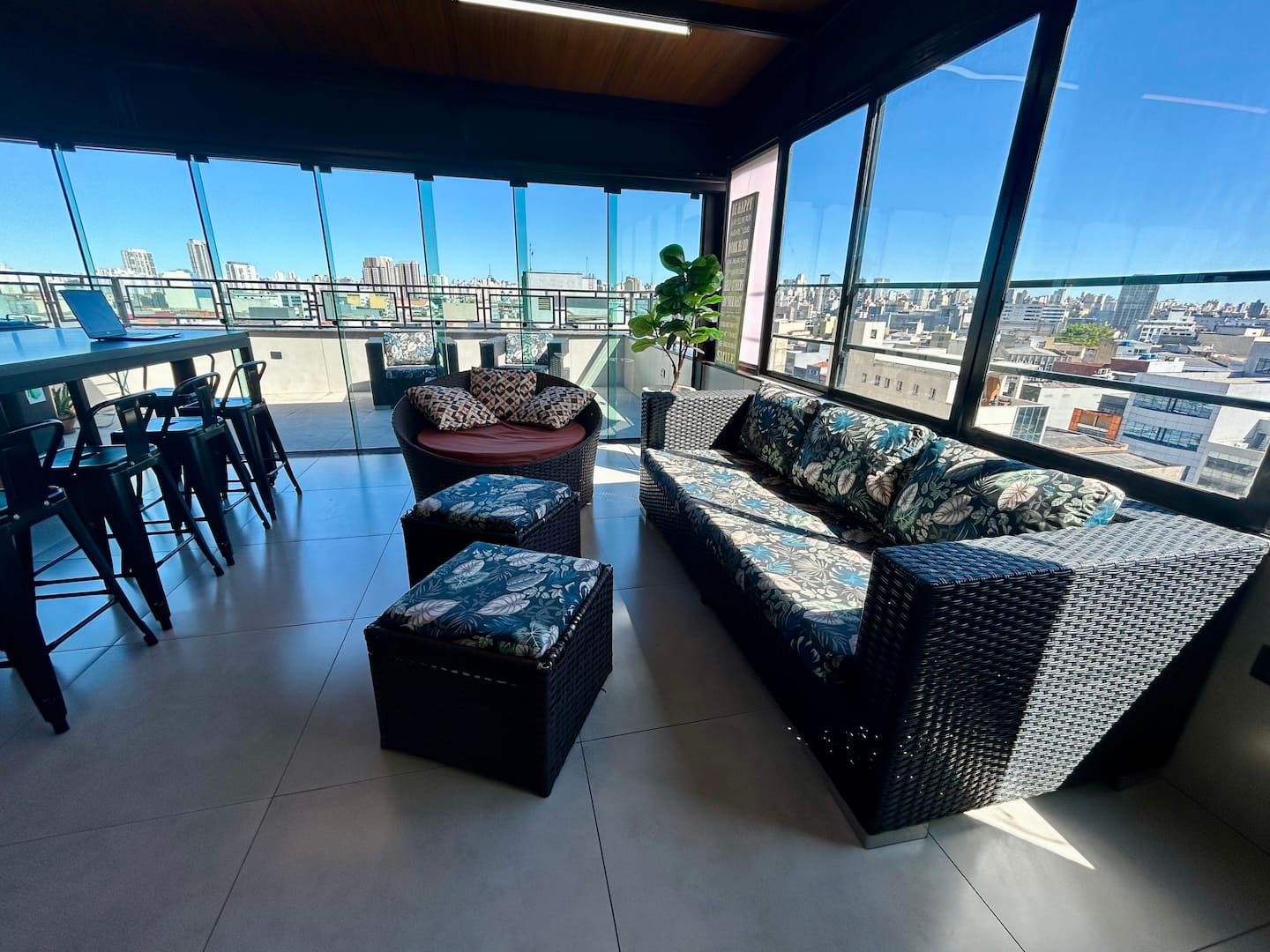 Lounge envidraçado com sofás e vista para São Paulo