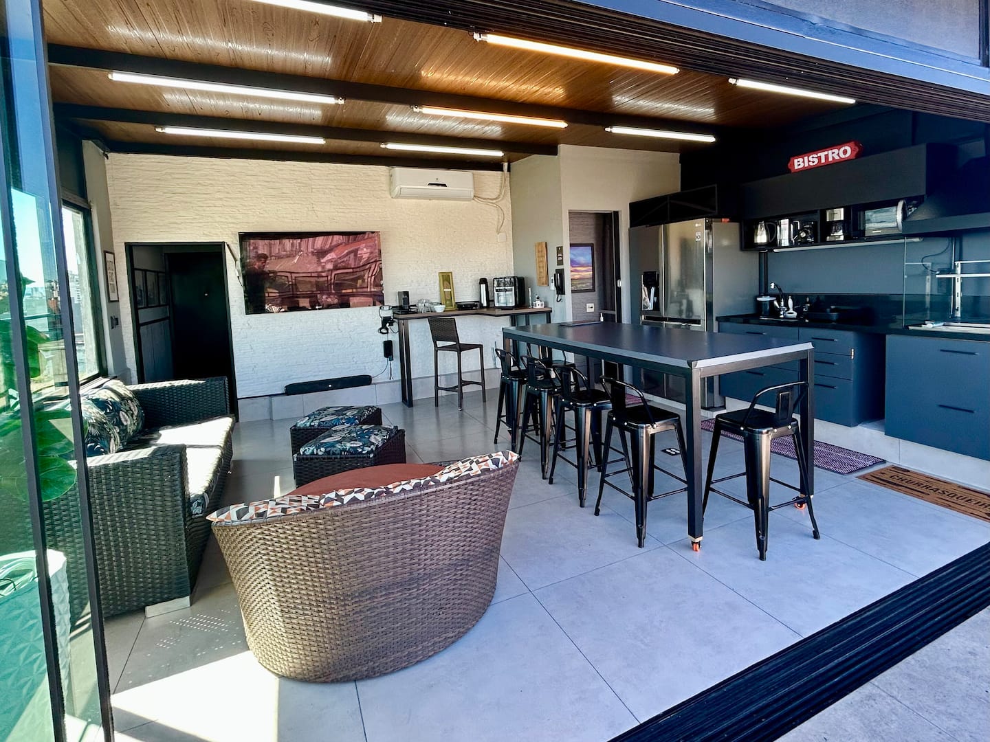 Espaço bistrô com balcão, banquetas e cozinha integrada